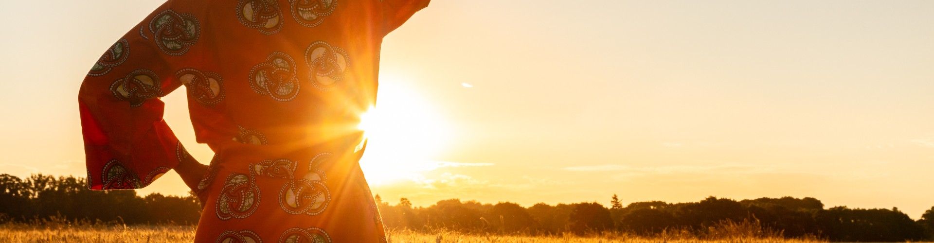 African woman dressed in traditional clothes looking at the sunset